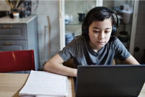 middle school-age male wearing headphones and using computer